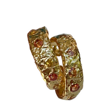 Load image into Gallery viewer, Gold hoop earring with embedded stones held by a hand on a light background