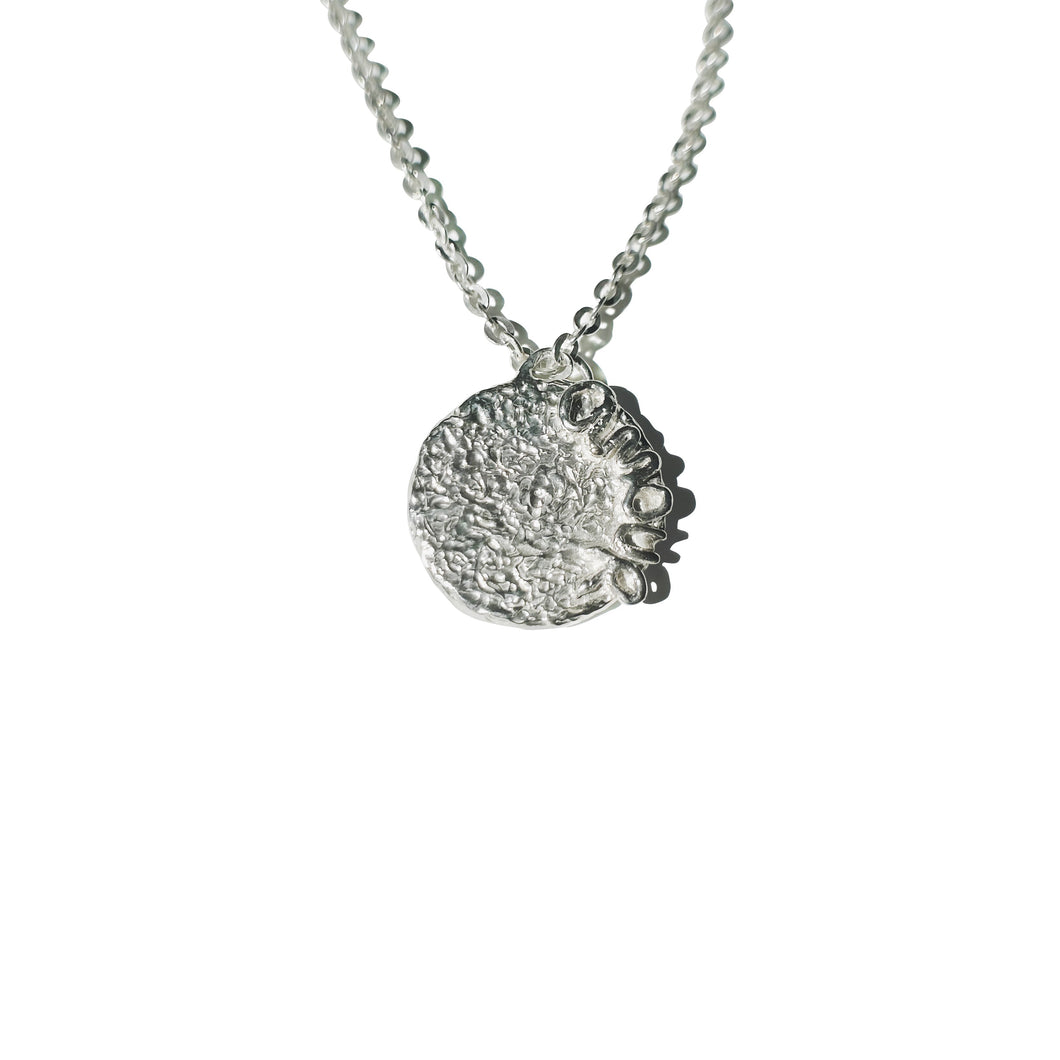 Silver necklace with a textured pendant on a white background

